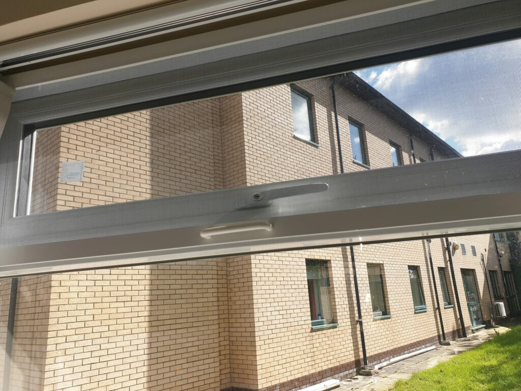 Hinged fly screen fitted to a commercial bakery window