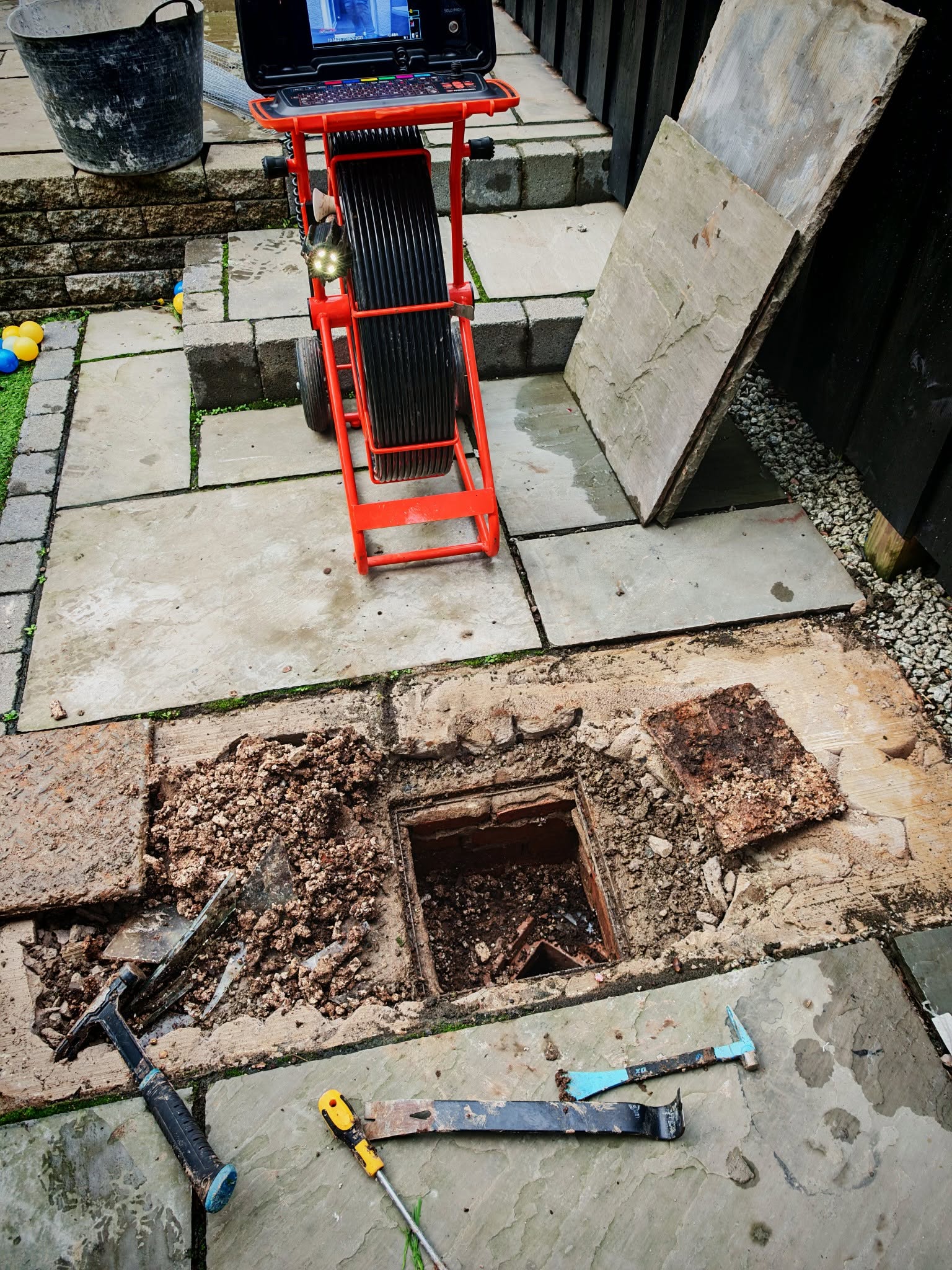 Red CCTV Drain survey tool next to exposed drain