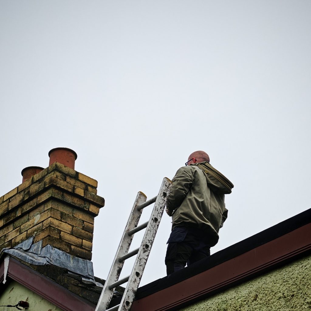 Pest controller on a roof removing a wasp nest 